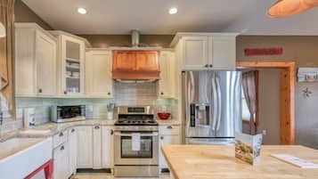 A kitchen with white cabinets, stainless steel appliances, a wooden table, and a farmhouse sign.