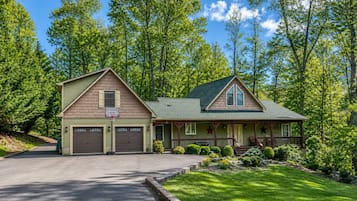 A two-story house with a garage, a porch with a railing, and a basketball hoop.