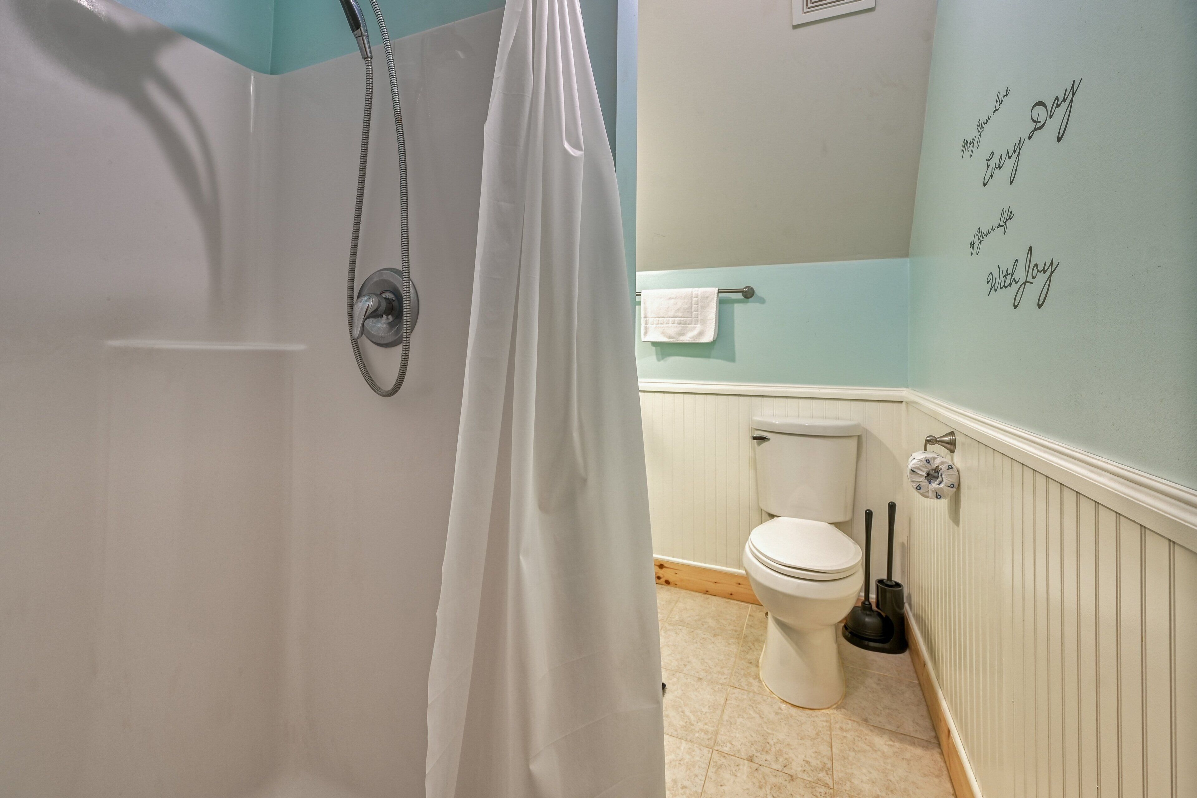 Un baño con ducha, inodoro y perchero para toallas.