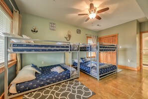 A bunk room with three bunk beds, a ceiling fan, and nautical-themed decor. - Lakefront Home With Private hot Tub, Dock, Grill, Game Room, Lake Views & Kayaks (Bumpass)
