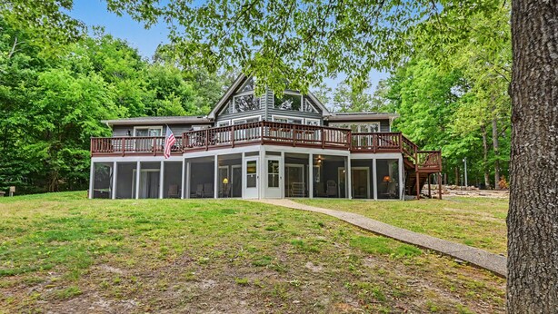 Ein zweistöckiges Haus mit Balkon, großen Fenstern und einer überdachten Veranda.