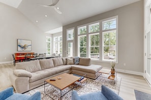 A spacious living room with a large sectional sofa, a coffee table, and a dining area with a table and chairs. - Spacious Lake House Retreat With Game Room, Theater Room, Fire pit and Boat Slip (Mineral)