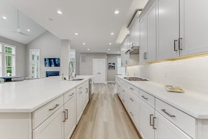 A modern kitchen with white cabinetry, a central island, and recessed ceiling lights. - Spacious Lake House Retreat With Game Room, Theater Room, Fire pit and Boat Slip (Mineral)