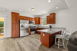 A modern kitchen with wooden cabinets, stainless steel appliances, and a granite countertop. - Lakeview Escape Near Beach With Fenced dog Run, Porch & Dock With one Boat Slip (Louisa)