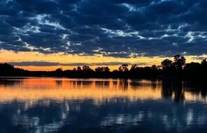 A calm lake at sunset with a dark sky and silhouettes of trees. - Lakeview Escape Near Beach With Fenced dog Run, Porch & Dock With one Boat Slip (Louisa)