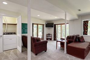 A living area with a sofa, a table, a TV, and a laundry area. - Lakefront Escape With Private Docks, Three-season Room, and Spacious Bunk Room (Mineral)