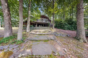 A stone pathway leading to a wooden cabin surrounded by trees.
