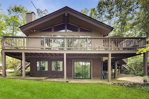 A two-story house with a balcony, large windows, and a stone foundation. - Lakefront Escape With Private Docks, Three-season Room, and Spacious Bunk Room (Mineral)
