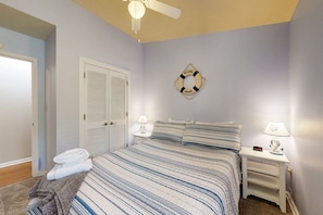 A bedroom with a bed, two bedside tables with lamps, a ceiling fan, a door, and a wall decoration. - Lakefront Escape With Private Docks, Three-season Room, and Spacious Bunk Room (Mineral)