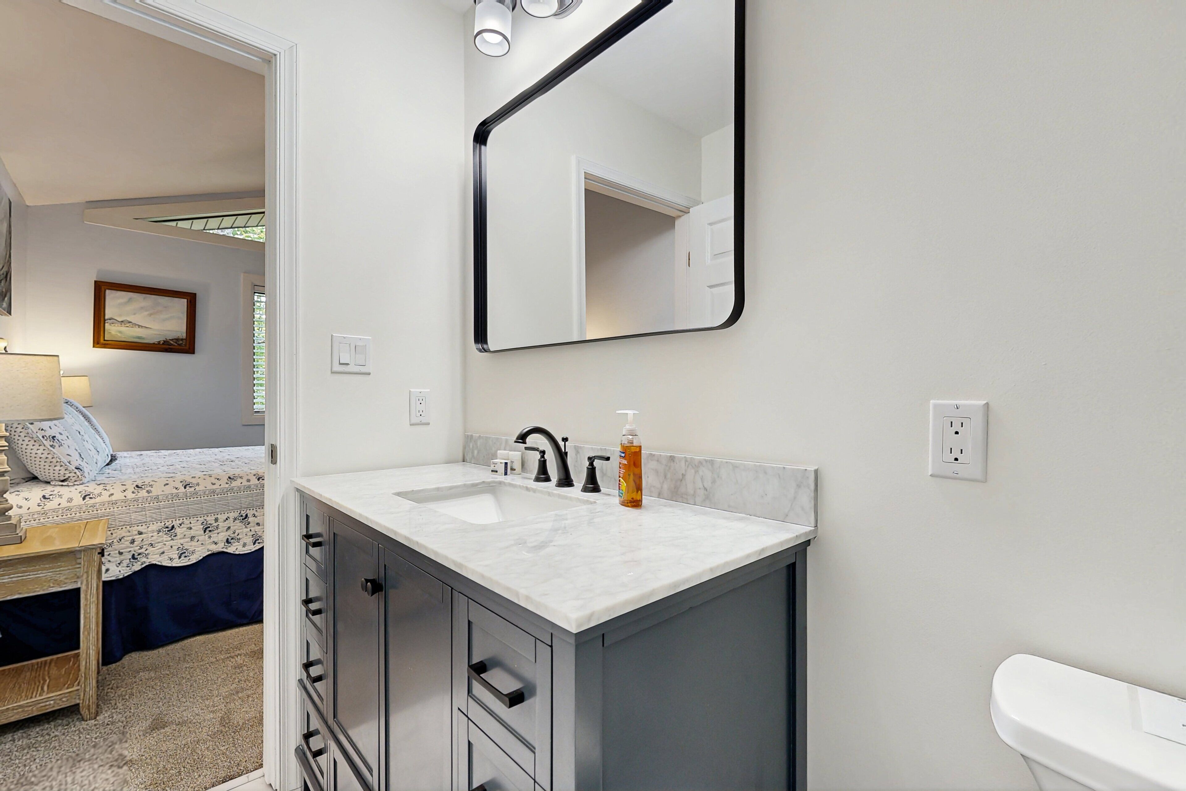Une salle de bain avec un lavabo blanc, un miroir et des toilettes.