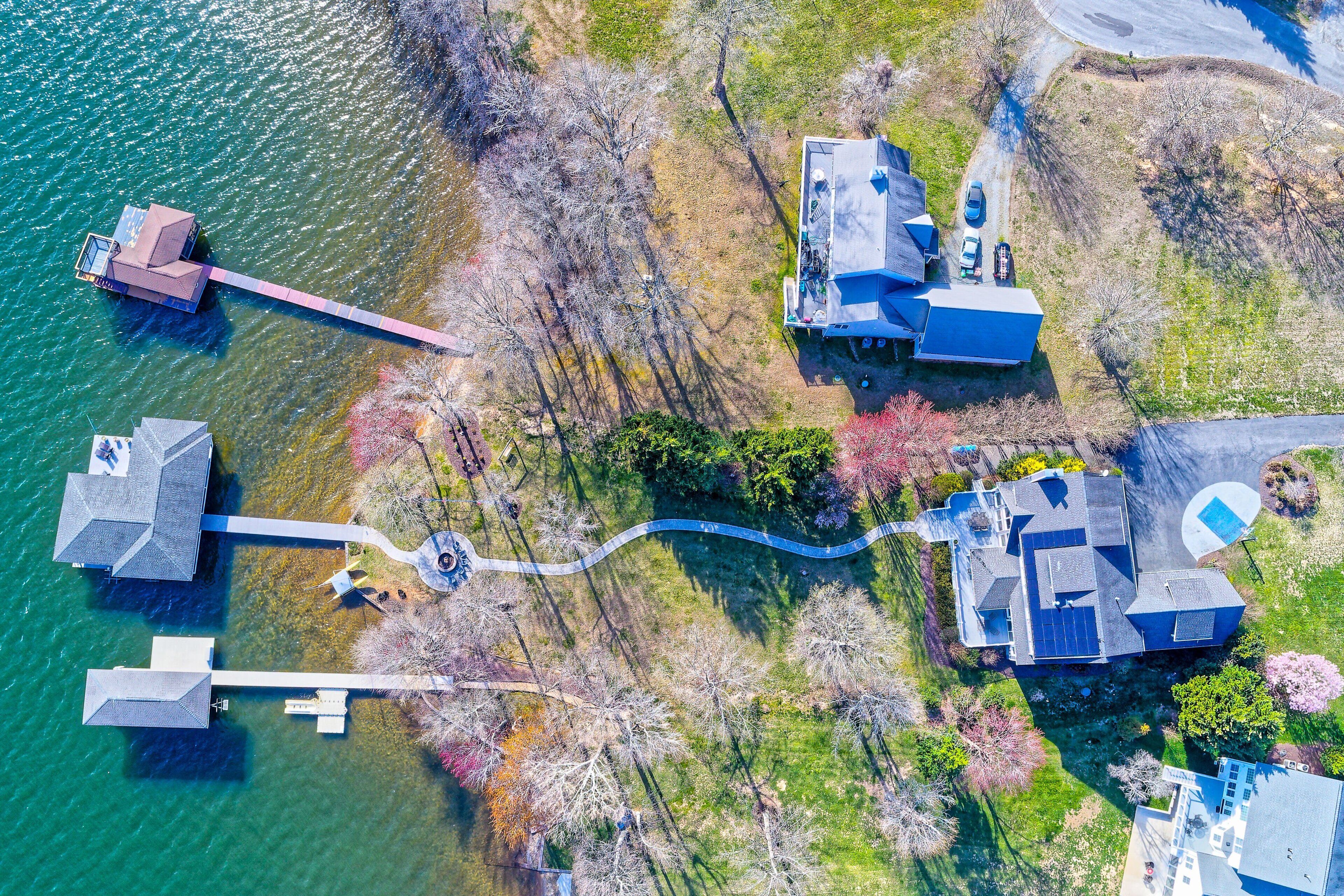 An aerial view of a lakeside property with multiple buildings, docks, and a winding pathway.