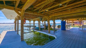 A wooden deck with a pool, outdoor seating, and a view of the water. - Large Lakefront Home on the Best Part of the Lake Spacious With Stunning Views (Bumpass)