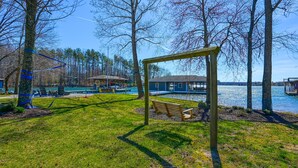 A lakeside park with a wooden swing set, a bench, and a gazebo. - Large Lakefront Home on the Best Part of the Lake Spacious With Stunning Views (Bumpass)