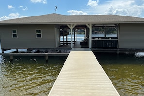 A waterfront building with a covered deck and a dock extending into the water. - Relaxing Lakeside Retreat With Boathouse, Dock, Deck, Firepit and Screened Porch (Bumpass)