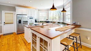 Una cocina con armarios blancos, una isla de madera y un ventanal grande.