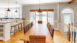 Un comedor amplio con una larga mesa de madera, techos altos y ventanas grandes.