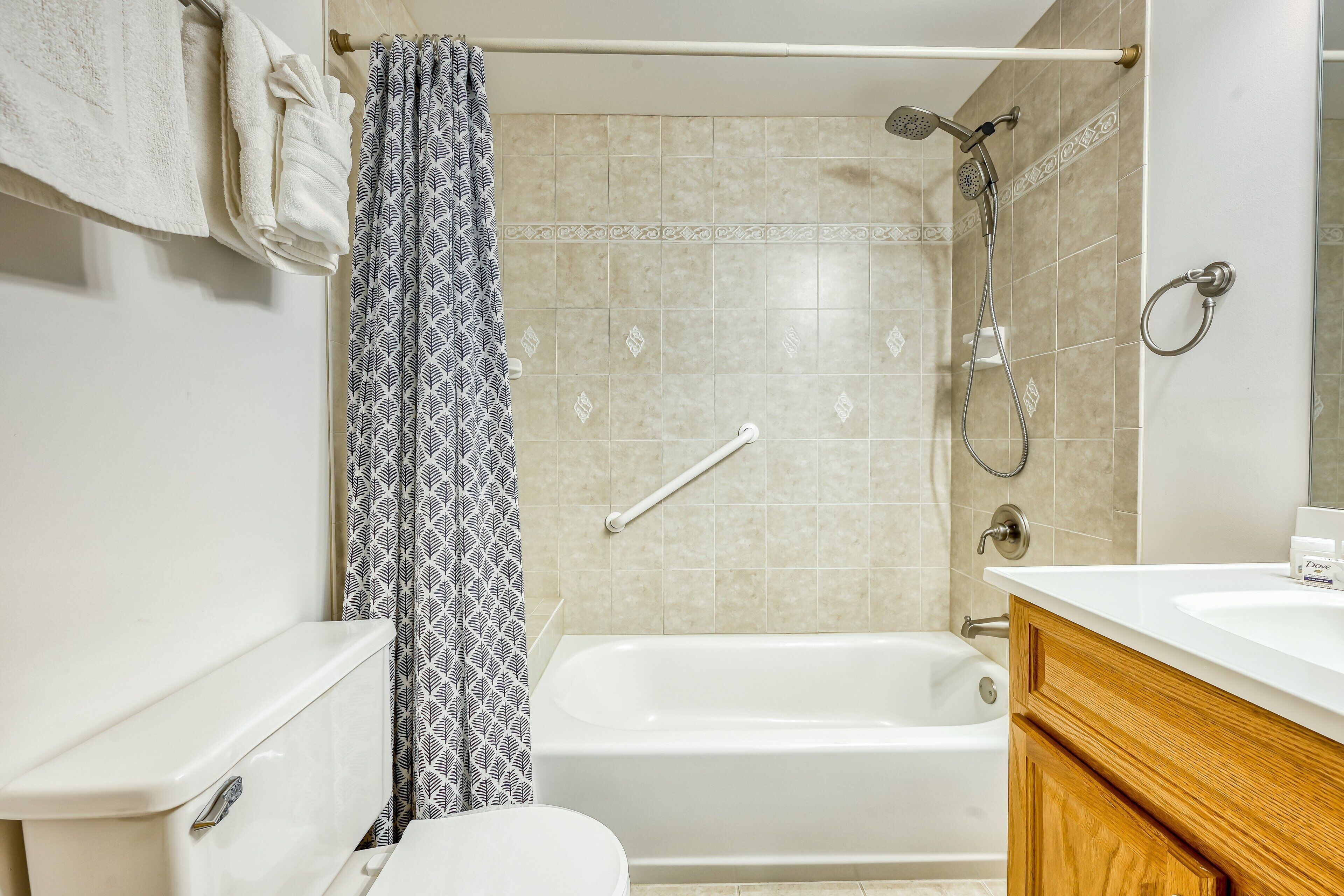 Ein Badezimmer mit Toilette, Badewanne, Dusche, Handtuchhalter und Waschbecken.