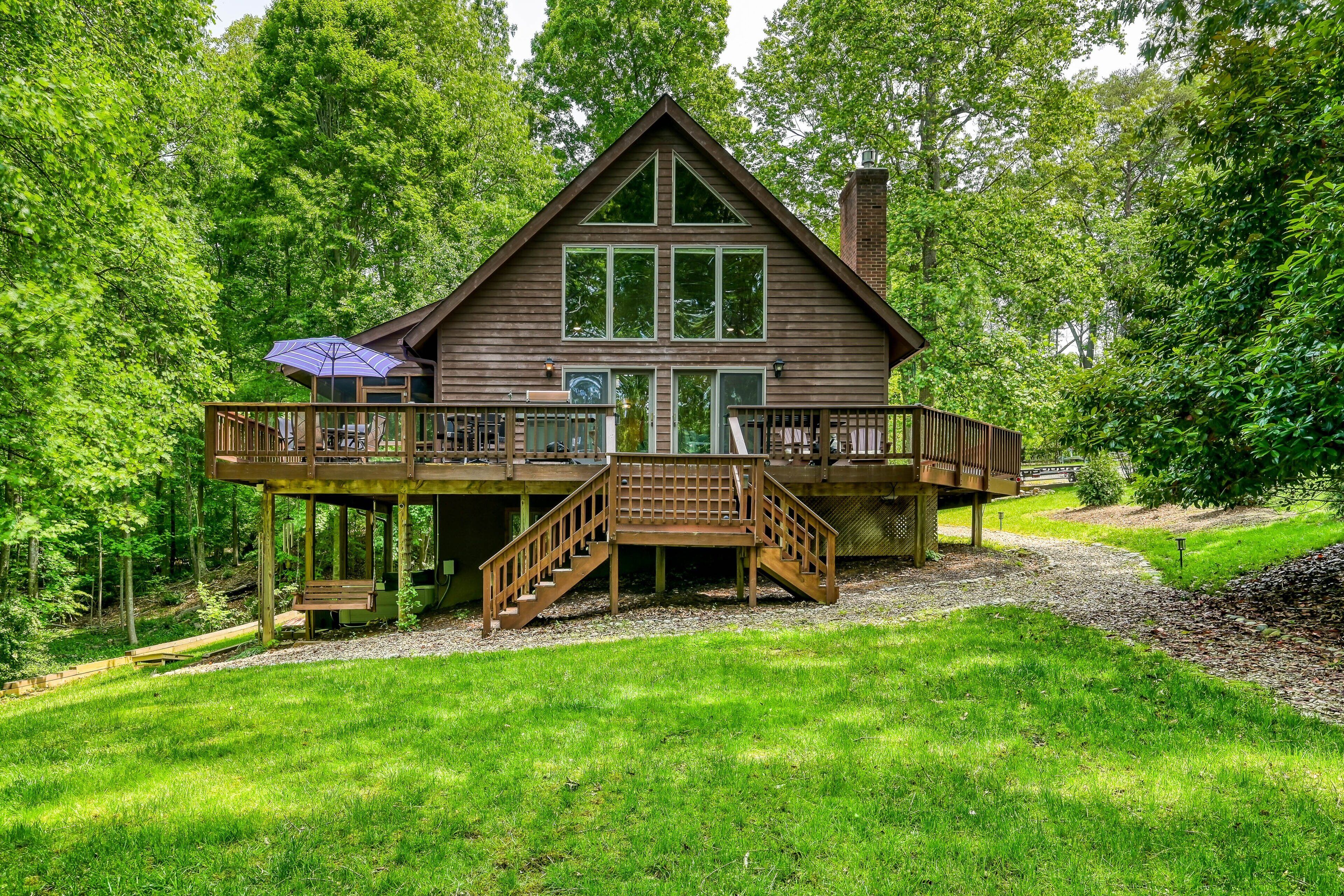 A wooden cabin with a deck, stairs, and a covered outdoor seating area.