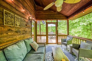 Ein Holzinterieur mit einer Couch, Sesseln und Blick ins Freie.