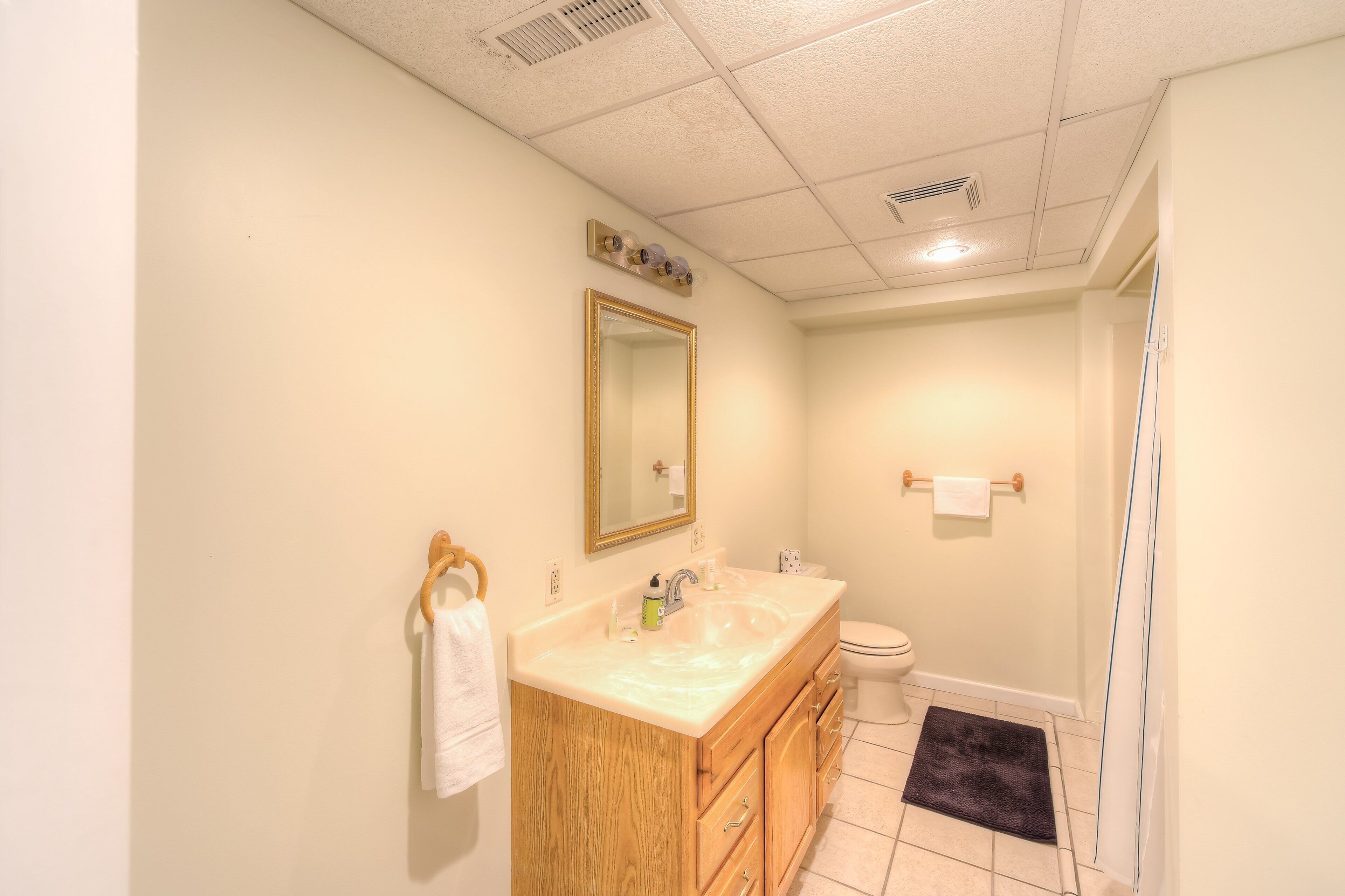 A bathroom with a sink, mirror, toilet, and shower.