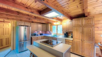 A kitchen with wooden cabinets, a stainless steel refrigerator, and a central island with a built-in stove.