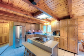 A kitchen with wooden cabinets, a stainless steel refrigerator, and a central island with a built-in stove. - Three-story Dog-friendly Home With Large Deck, Wood Swing, Firepit, Lawn, & More (Mineral)