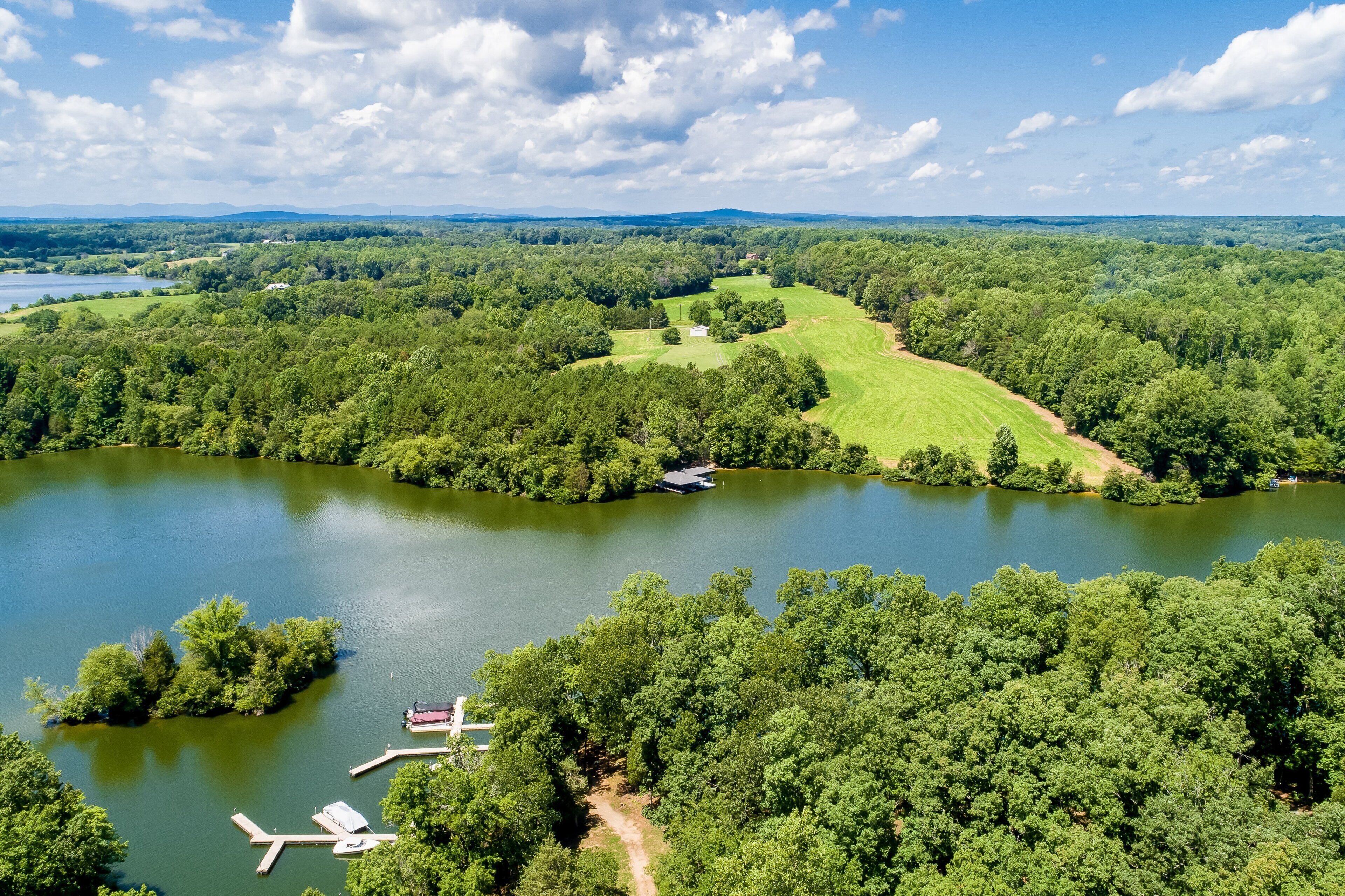 A lake surrounded by dense forest, a small dock, and a distant hill.