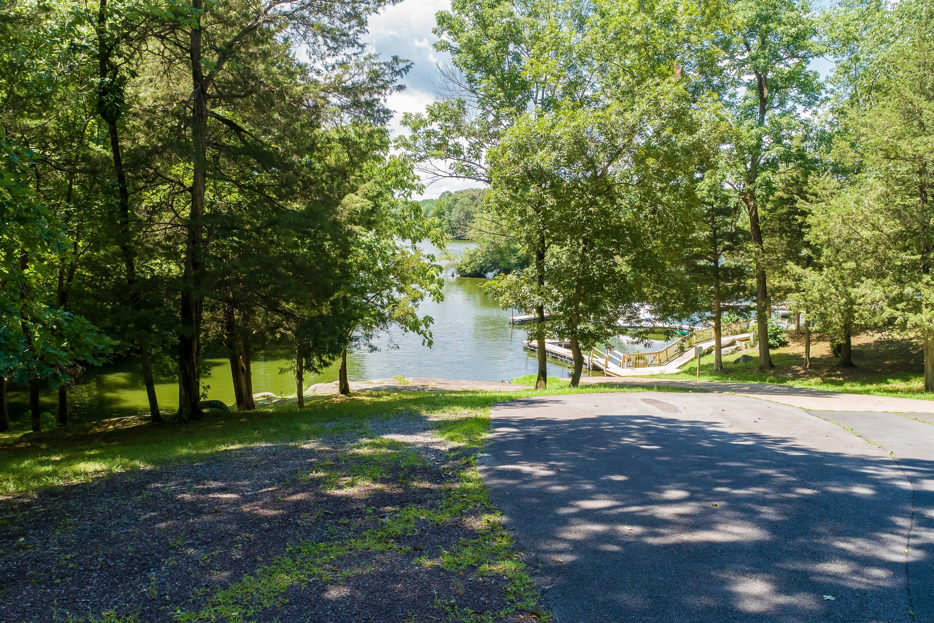 A paved pathway leading to a lake surrounded by trees.