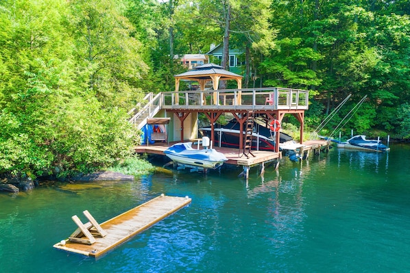 Ein Hausboot liegt an einem Steg, umgeben von üppigem Grün.