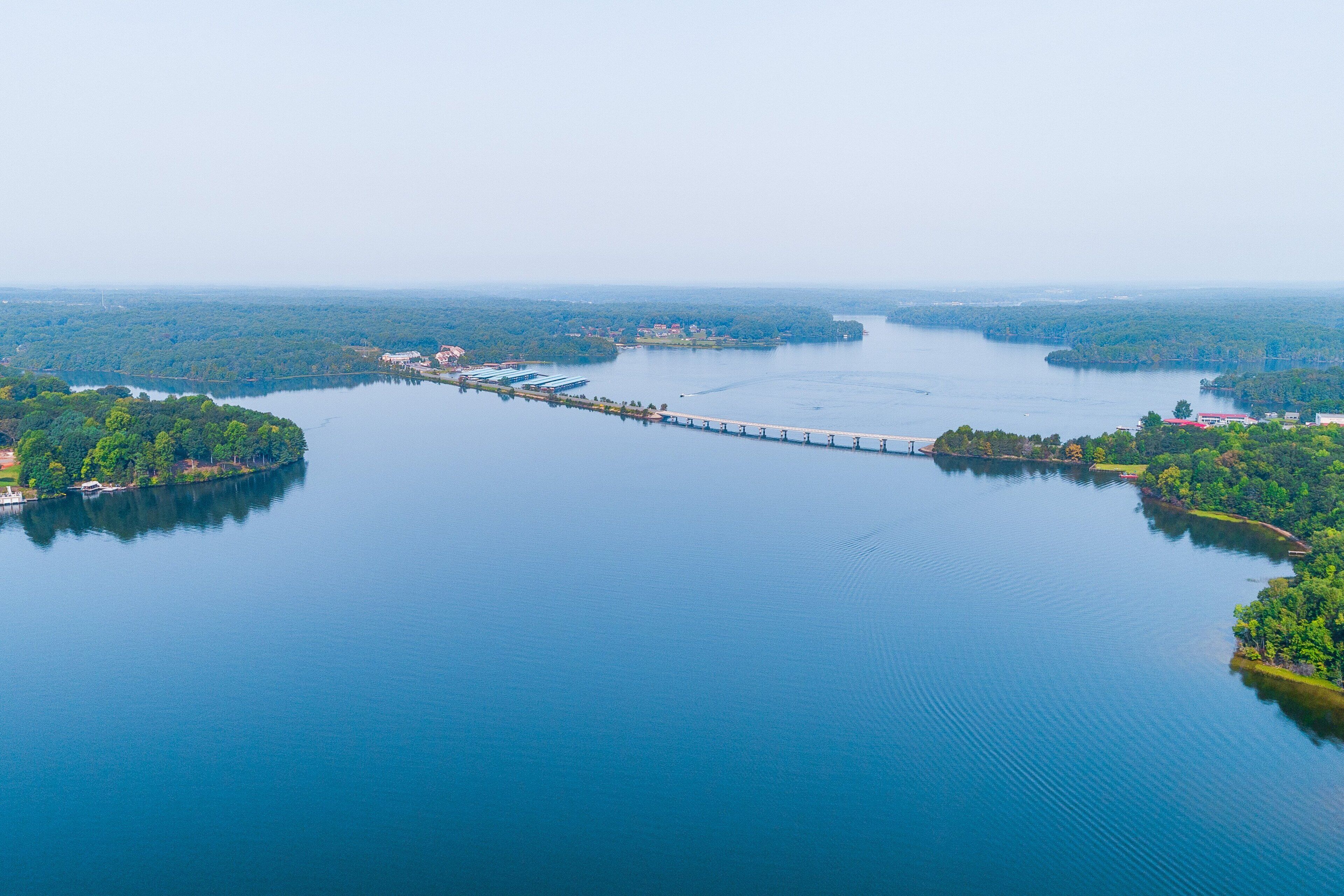 An aerial view of a large body of water with a bridge connecting two landmasses.