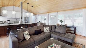 A modern living room with a sectional sofa, a coffee table, and a kitchen in the background.