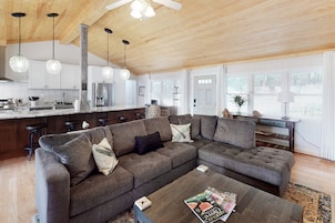A modern living room with a sectional sofa, a coffee table, and a kitchen in the background.