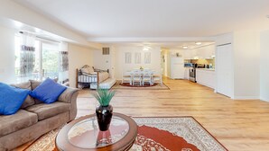 A spacious living area with a sofa, coffee table, and a dining table in the background.