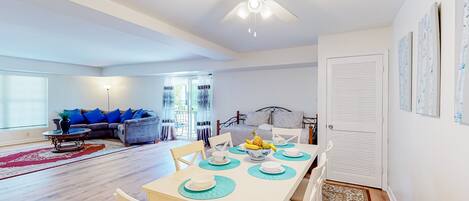 Un salon moderne avec un coin repas, un ventilateur de plafond et une vue sur la chambre adjacente.