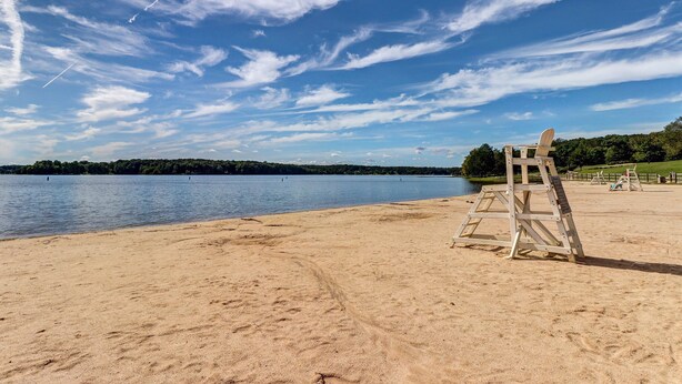 A beach with a lifeguard stand, calm water, and a clear sky.
