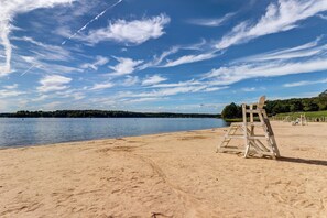 A beach with a lifeguard stand, calm water, and a clear sky.