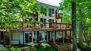A two-story house with a deck, large windows, and a covered patio area. - Spacious Lake Lodge With a Private Dock, Wraparound Decks & Foosball (Mineral)