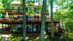 A multi-level wooden house with a deck, surrounded by trees. - Spacious Lake Lodge With a Private Dock, Wraparound Decks & Foosball (Mineral)
