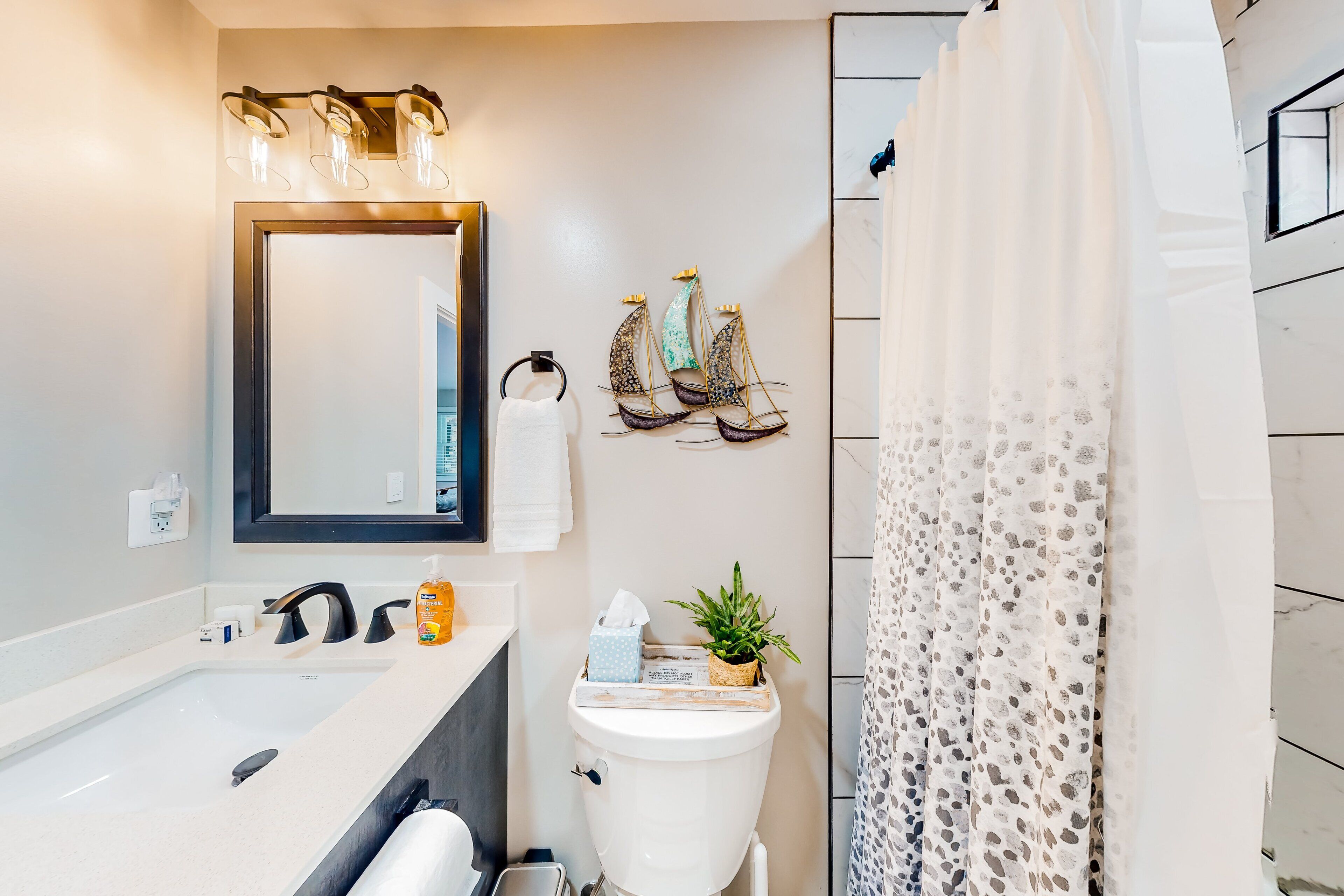 Een badkamer met een wit wastafel, een spiegel, een handdoekhouder, een toilet en een douchegordijn.