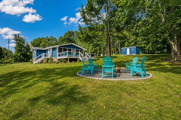 Ein Haus mit Veranda, Terrasse und Feuerstelle mit Sitzgelegenheiten.