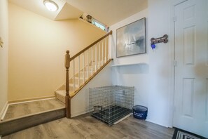A staircase with wooden railings, a metal pet cage, a framed artwork, and a door with a sign. - Spacious pet Friendly Waterfront House With Patio & Grill (Bumpass)