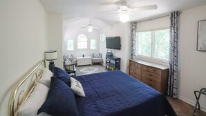 A bedroom with a bed, a desk, a television, and a ceiling fan. - Spacious pet Friendly Waterfront House With Patio & Grill (Bumpass)