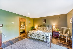 Een slaapkamer met een bed, nachtkastje, stoel en spiegel.