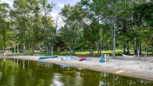 En park vid sjön med träd, en sandstrand och ett område för picknick.