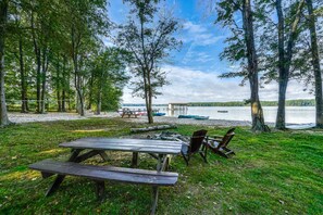 A lakeside picnic area with benches and a table, surrounded by trees and a view of the lake. - Lakefront Retreat With Dock, Private Hot Tub, Central AC, and Private Beach (Bumpass)