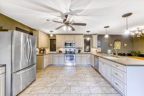 A modern kitchen with a stainless steel refrigerator, a built-in oven, and a ceiling fan. - Lakefront Retreat With Dock, Private Hot Tub, Central AC, and Private Beach (Bumpass)