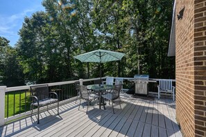 A deck with a table and chairs, a grill, and a white railing. - Lakefront Family Home in Gated Community With Swimming Area & Dock - Dogs OK (Bumpass)
