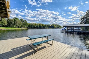 A wooden dock with a picnic table, a covered seating area with a slide, and a lake view. - Lakefront Family Home in Gated Community With Swimming Area & Dock - Dogs OK (Bumpass)