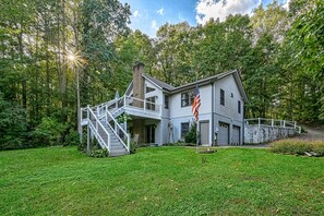 A two-story house with a front porch, a staircase, and a flagpole. - Lakefront Family Home in Gated Community With Swimming Area & Dock - Dogs OK (Bumpass)