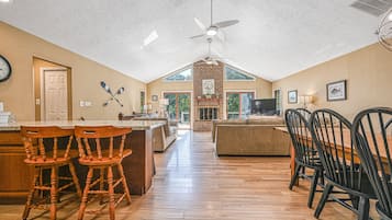 A spacious kitchen with wooden flooring, a central island, and a dining area with chairs.